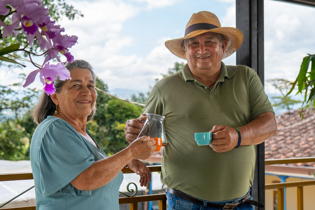 Pareja adulta disfrutando una cata de cafés en finca colombiana con vista natural y ambiente relajado