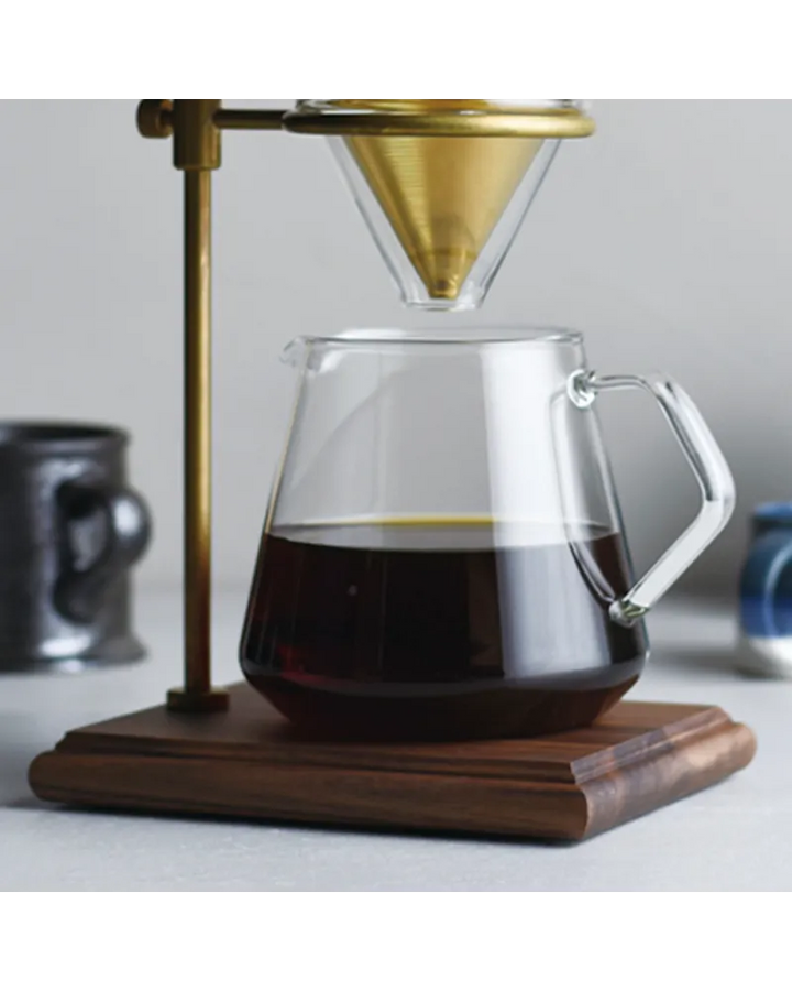 Jarra de café Kinto de vidrio con capacidad de 600 ml sobre base de madera, diseñada para un servicio artesanal elegante y funcional.